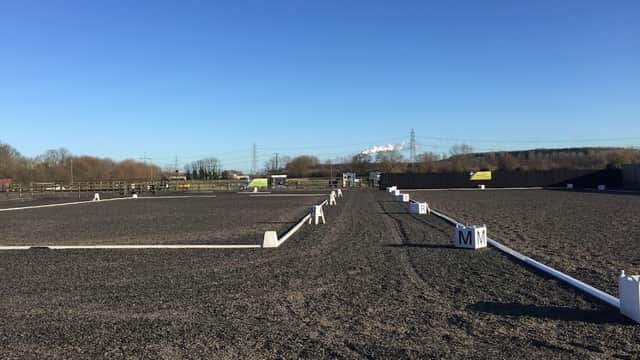 Wide view of a dressage arena with white markers, surrounded by a clear blue sky and distant hills in Yorkshire.