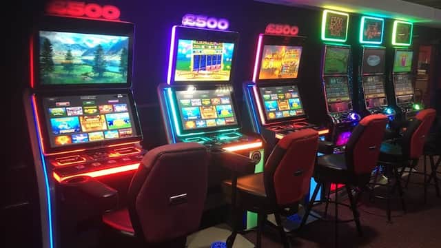 Brightly lit slot machines with colorful screens and chairs in a gaming area at Buzz Bingo, Barnsley.