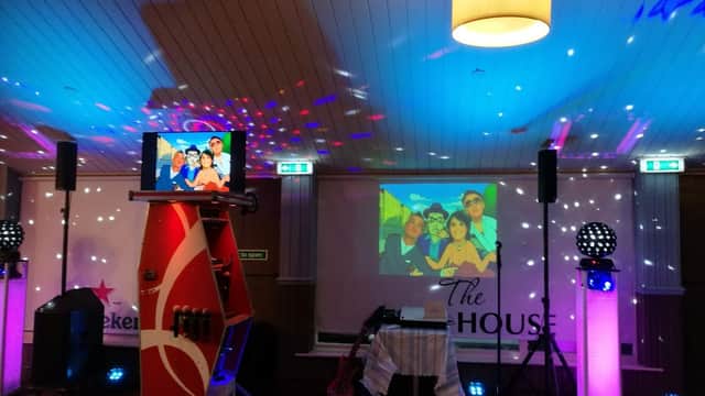 A vibrant bar interior with colorful lights, a karaoke machine, and screens displaying animated characters.