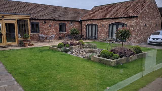 Charming hotel courtyard with landscaped garden, stone pathways, and modern seating areas.