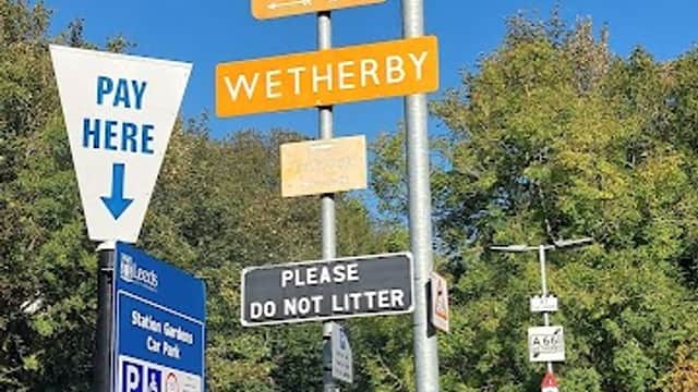Signpost indicating parking zones 1 & 2, Wetherby; "Please do not litter" notice, clear blue sky above.
