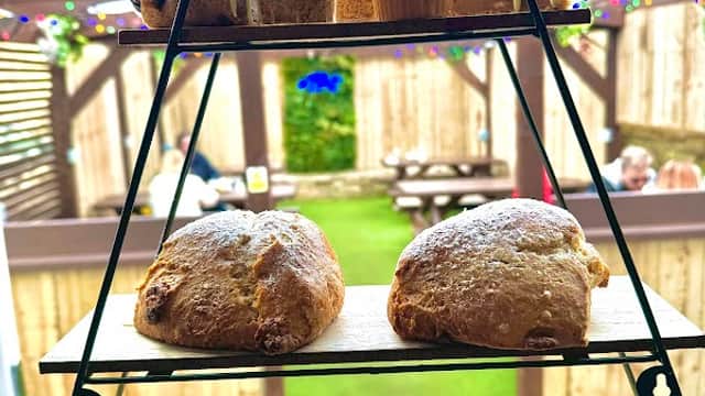 Tiered stand displaying an assortment of cakes, pastries, and sandwiches, set in a cozy outdoor tearoom.