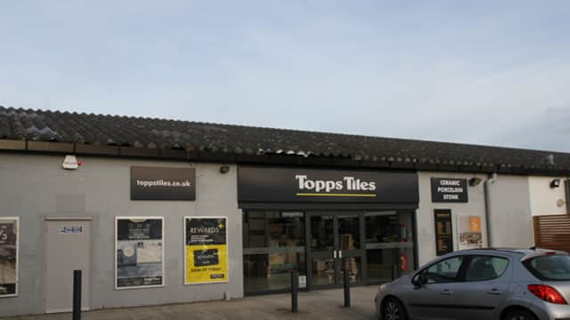 Topps Tiles store exterior in Harrogate, featuring large glass entrance and signage, with parked car in front.