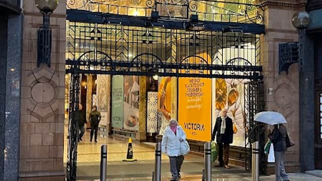 Entrance to County Arcade with ornate archway, shoppers, and wet pavement reflecting lights.