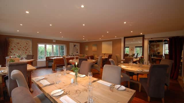 Cozy restaurant interior with wooden tables, upholstered chairs, and soft lighting, featuring a welcoming atmosphere.