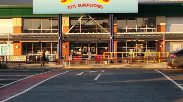 Smyths Toys Superstores storefront with bright signage, large windows, and a clear blue sky above.