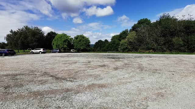 Gravel parking lot at Concord Park in Carbrook, Yorkshire, with scattered trees and a blue sky.