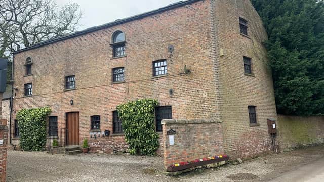 Brick building with arched windows, ivy-covered walls, and a gravel path in Bilbrough, Yorkshire.