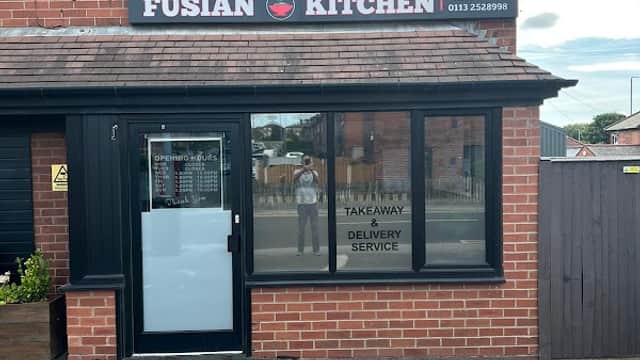Fusian Kitchen restaurant with a red brick exterior, large windows, and a sign indicating takeaway and delivery services.