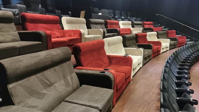 Rows of plush, colorful cinema seats in a modern theater, featuring red, white, and brown upholstery.