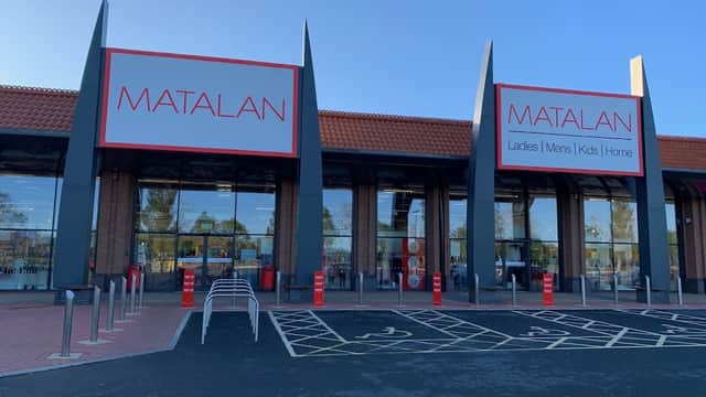 Matalan storefront with large signage, featuring sections for ladies, men, kids, and home. Clear blue sky above.