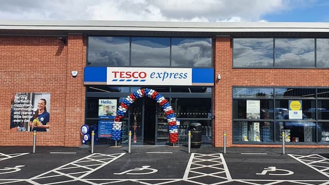 Tesco Express storefront with blue and red balloon arch, signage, and parking spaces in Darfield, Yorkshire.