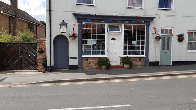Quaint fish restaurant with large windows, colorful bunting, flower pots, and a blue door in Nafferton, Yorkshire.