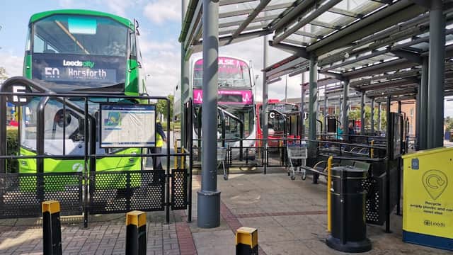 Seacroft bus station featuring multiple buses, waiting areas, and recycling bins under a covered structure.
