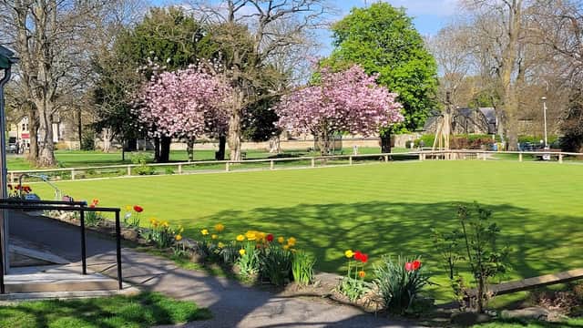 Lush green park with blooming cherry trees, colorful tulips, and a pathway leading to a bowling green in Burley.