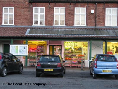 Corner shop with colorful displays, parked cars in front, and large windows showcasing various products in York.