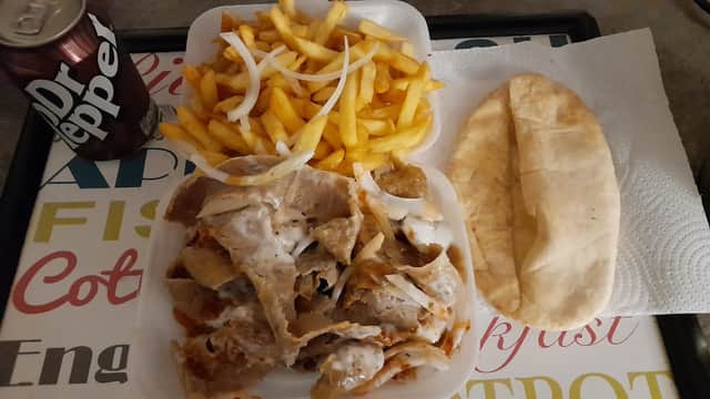 A tray with fries, nachos topped with sauce and onions, a pita bread, and a can of Dr Pepper.