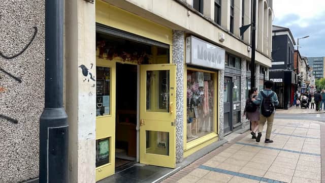 Bright yellow storefront of Moonko florist, with floral displays visible in the windows, situated on a busy street.