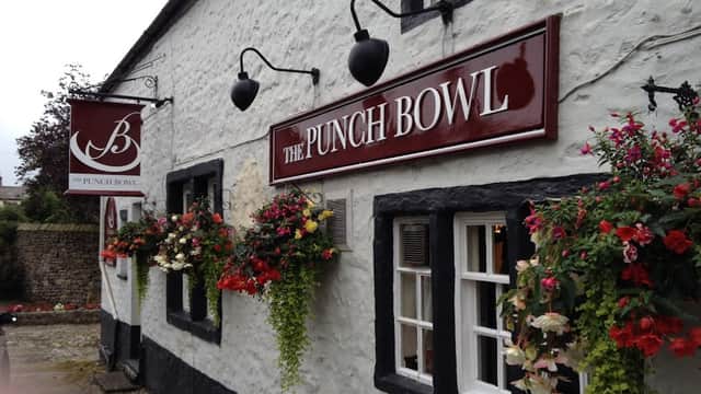 The Punch Bowl Inn features a whitewashed exterior, black trim, and vibrant flower baskets adorning the windows.