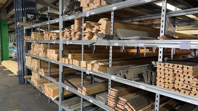 Shelves stocked with various wooden planks, metal sheets, and building materials in a hardware store.