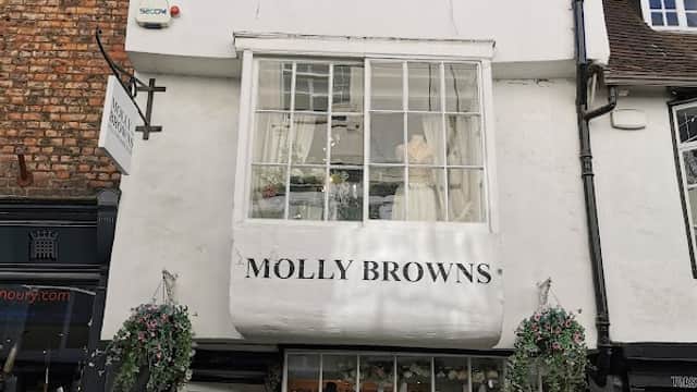 Molly Browns shopfront featuring elegant dresses, large windows, and floral decorations in York, Yorkshire.