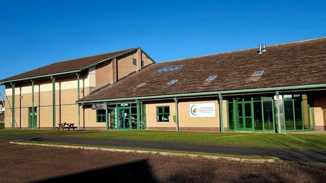 Modern sports center with large green windows, a sloped roof, and a clear blue sky in Colburn, North Yorkshire.