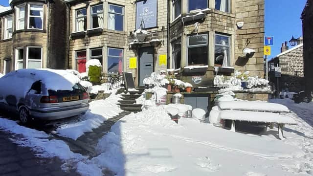 The Cross Inn bar covered in snow, with a parked car and outdoor seating visible in a winter scene.
