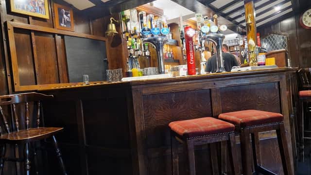 Cozy bar interior with wooden furnishings, beer taps, and a bartender in the background at Highwayman Inn, Sheriff Hutton.