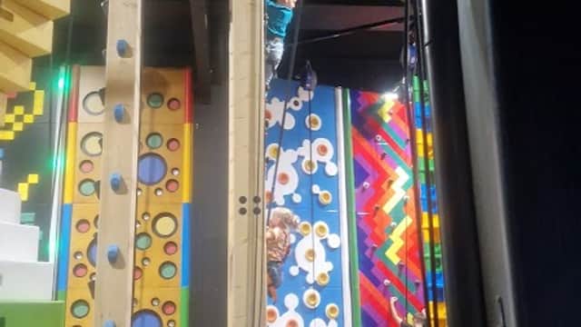 Indoor climbing area with colorful walls, climbing holds, and people engaged in climbing activities.