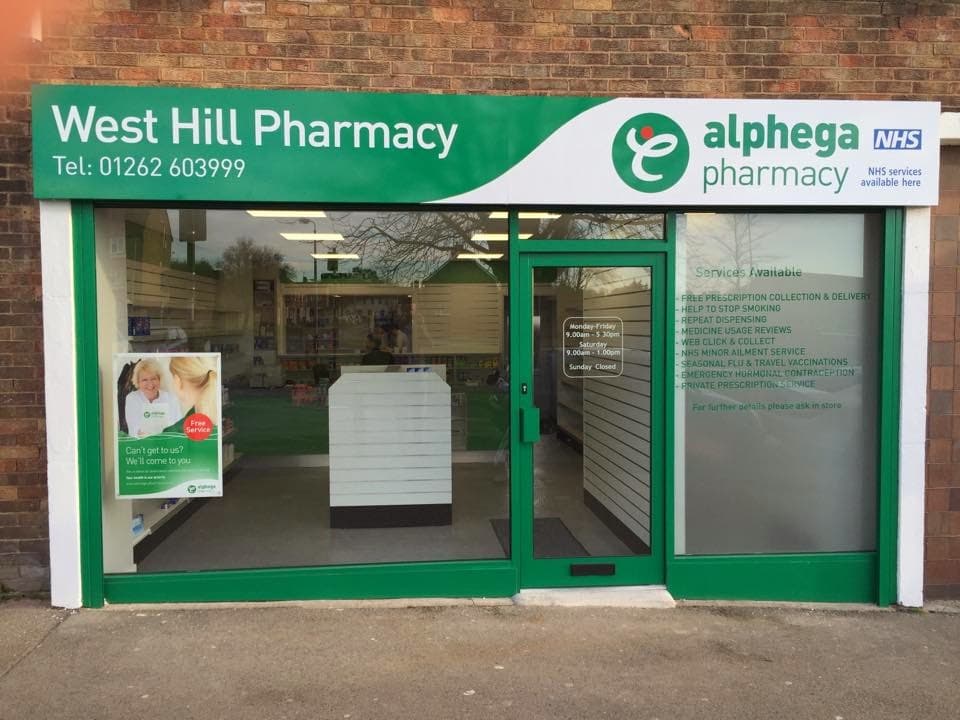 West Hill Pharmacy storefront with signage for ear wax removal, travel, and weight loss services in Bessingby, Yorkshire.