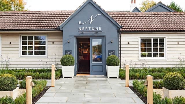 Charming homeware store with a grey facade, large windows, and neatly trimmed boxwood plants flanking the entrance.