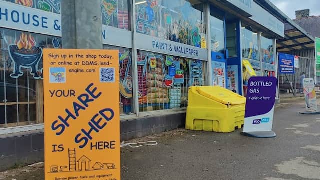 Colorful storefront of Scissett DIY featuring paint and wallpaper, with signs for services and products outside.