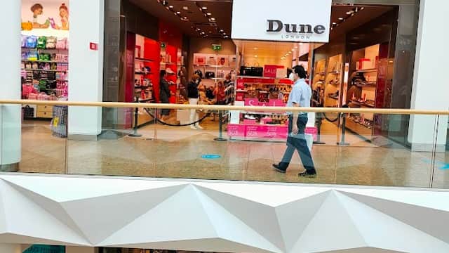 Shoe shop "Dune" in a mall, featuring bright displays and shoppers browsing inside.