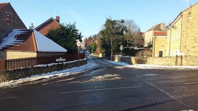Quiet street in Anston, Yorkshire, with snow on the ground, lined by houses and trees under a clear blue sky.