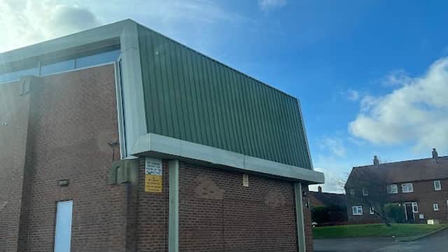 Netherton Village Hall featuring a green roof, brick exterior, and clear blue sky in the background.