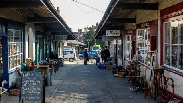 Shambles Car Park in Malton, Yorkshire, featuring shops, antiques, and a cobbled walkway under a covered arcade.