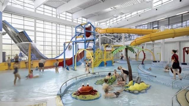 Indoor water park featuring slides, pools, and families enjoying the facilities under large windows.