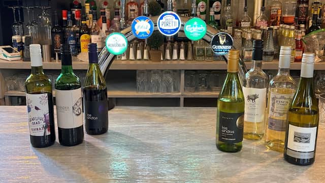 Bistro bar with various bottles of wine and spirits on display, illuminated by colorful signage in a cozy setting.