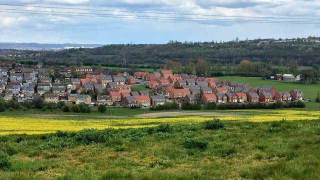 View of Topcliffe Grange Farm amidst green fields and residential homes under a cloudy sky in Tingley, Yorkshire.