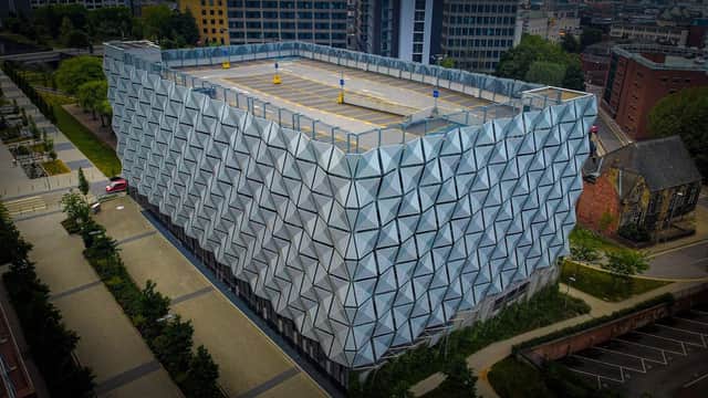 Modern multi-story car park with a geometric faΓ§ade, surrounded by greenery and urban buildings in Leeds, Yorkshire.