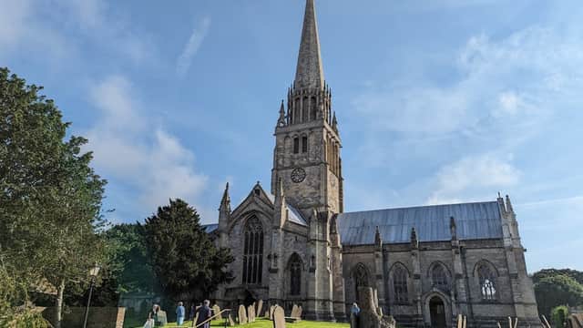 St Patrick's Church features a tall spire, stone architecture, and surrounding greenery with gravestones in the foreground.
