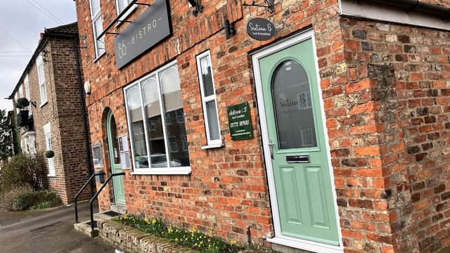 Brick building with a green door, signage for "Sixteen B" Bistro, and daffodils along the pathway in Dunnington, Yorkshire.