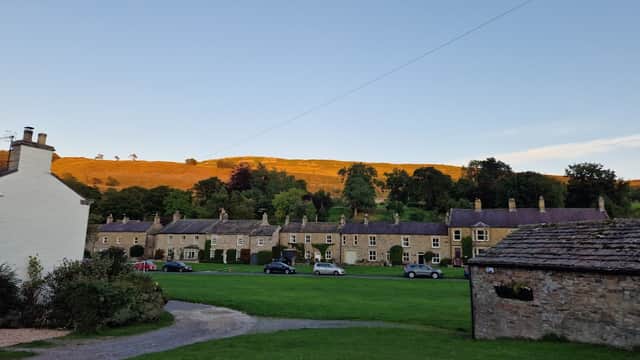 Charming hotel with stone buildings, green lawn, and a hillside bathed in warm sunset light in West Burton, Yorkshire.