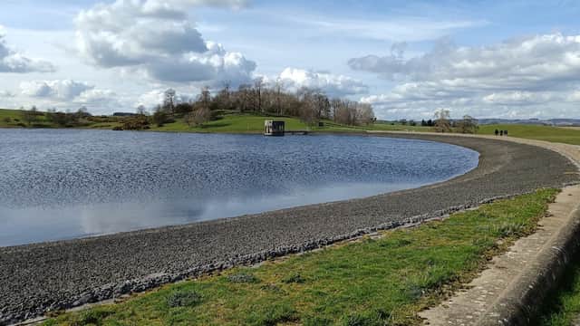 Car park near Thornton Steward Reservoir, with a calm water surface and grassy banks under a cloudy sky.