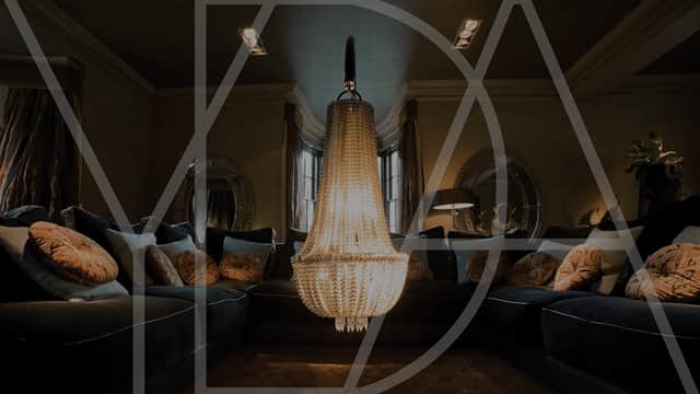 Elegant living room with a grand chandelier, plush sofas adorned with decorative cushions, and stylish lighting.