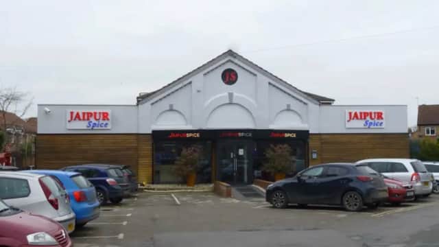 Jaipur Spice restaurant exterior with a modern design, featuring a sign, large windows, and parked cars in the lot.