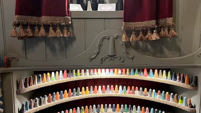 Colorful display of miniature gift items arranged in a tiered shelf, with red curtains framing the scene.