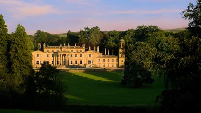 Elegant yellow stone hotel surrounded by lush greenery, with classical architecture and a serene landscape in Yorkshire.
