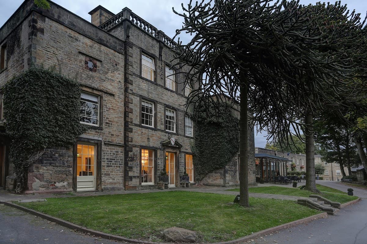 Historic stone building with ivy-covered walls, large windows, and surrounding greenery in Mosborough, Yorkshire.