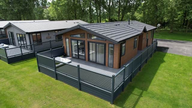 Modern lodge surrounded by greenery, featuring a spacious deck and privacy fencing in Wild Rose Country Park, Yorkshire.